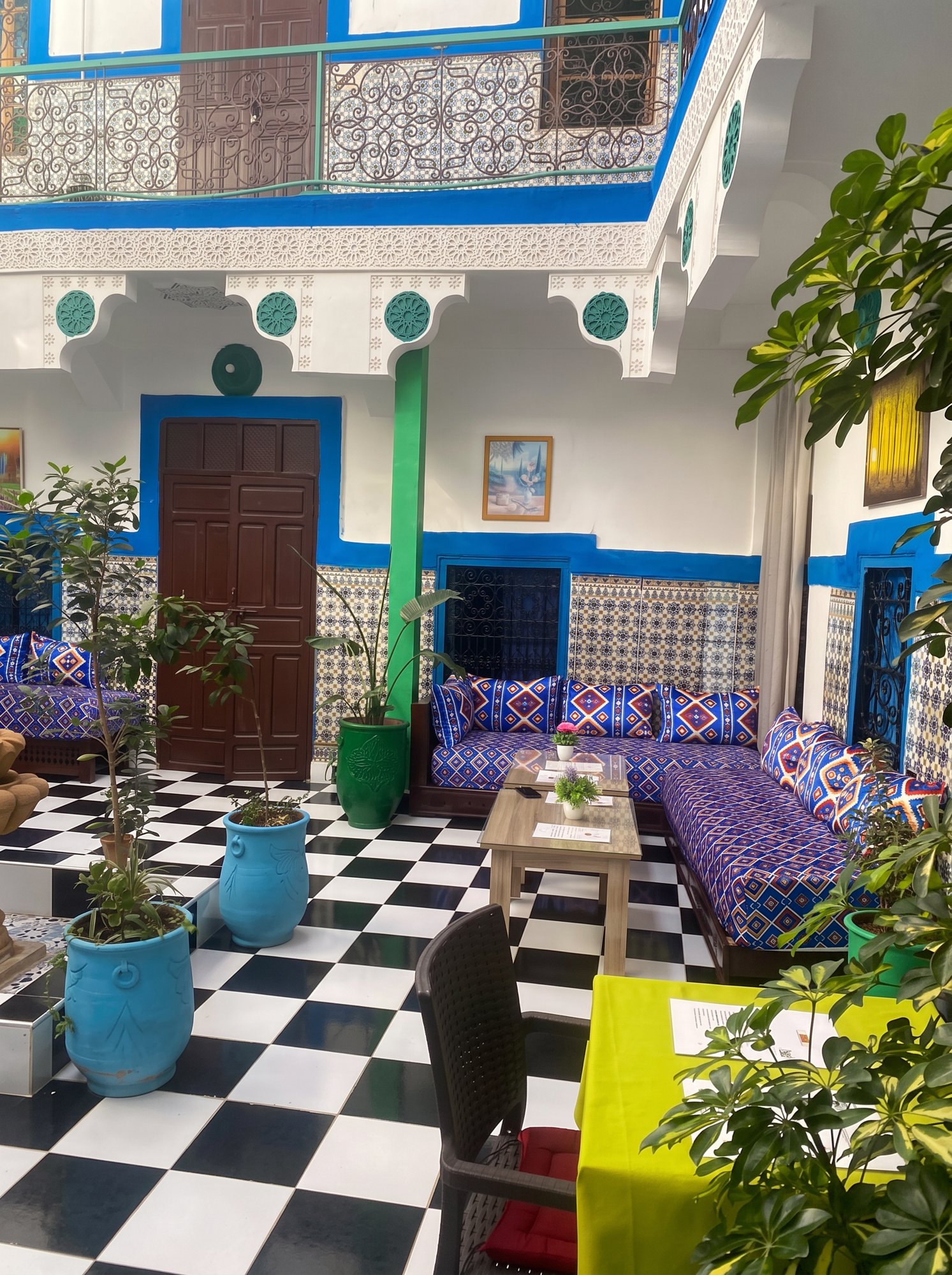 Terrasse du riad au coucher du soleil avec théière en argent, lanternes et minaret de la Koutoubia à l'horizon