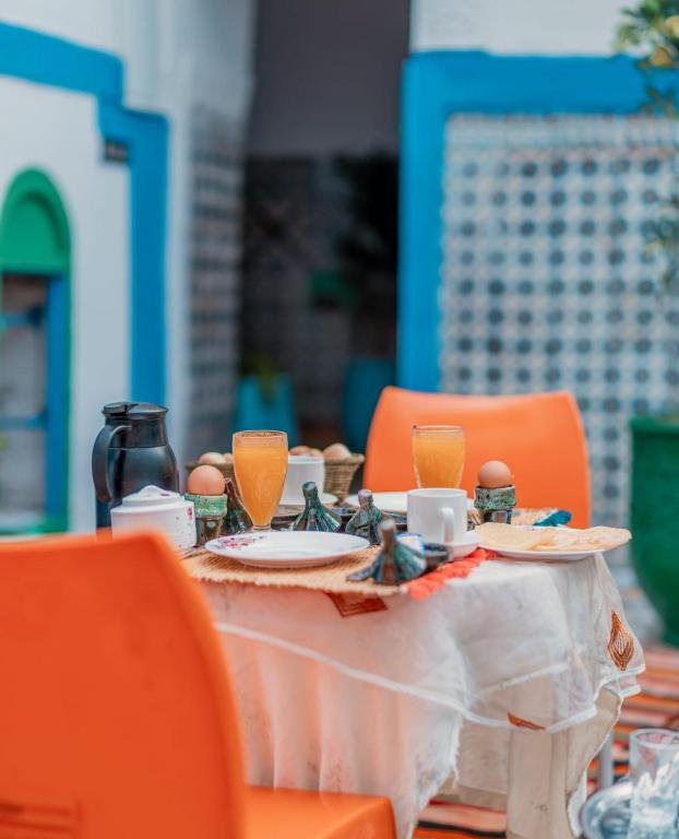 Petit-déjeuner continental servi dans le patio : crêpes marocaines, fruits frais, fromage et thé à la menthe