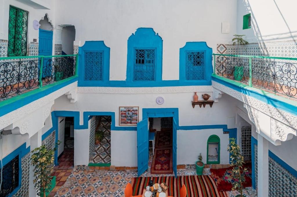 Terrasse du riad au coucher du soleil avec théière en argent, lanternes et minaret de la Koutoubia à l'horizon