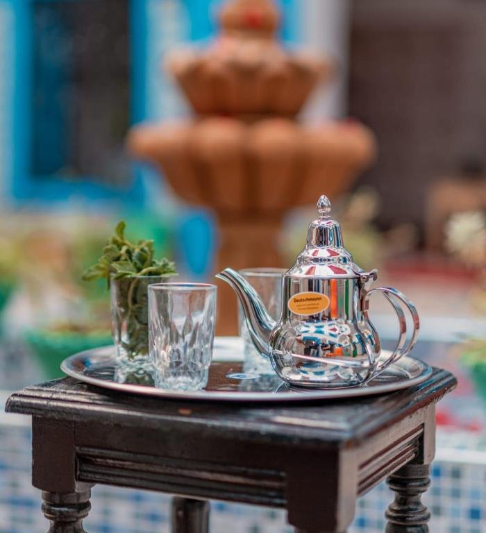 Petit-déjeuner continental servi dans le patio : crêpes marocaines, fruits frais, fromage et thé à la menthe